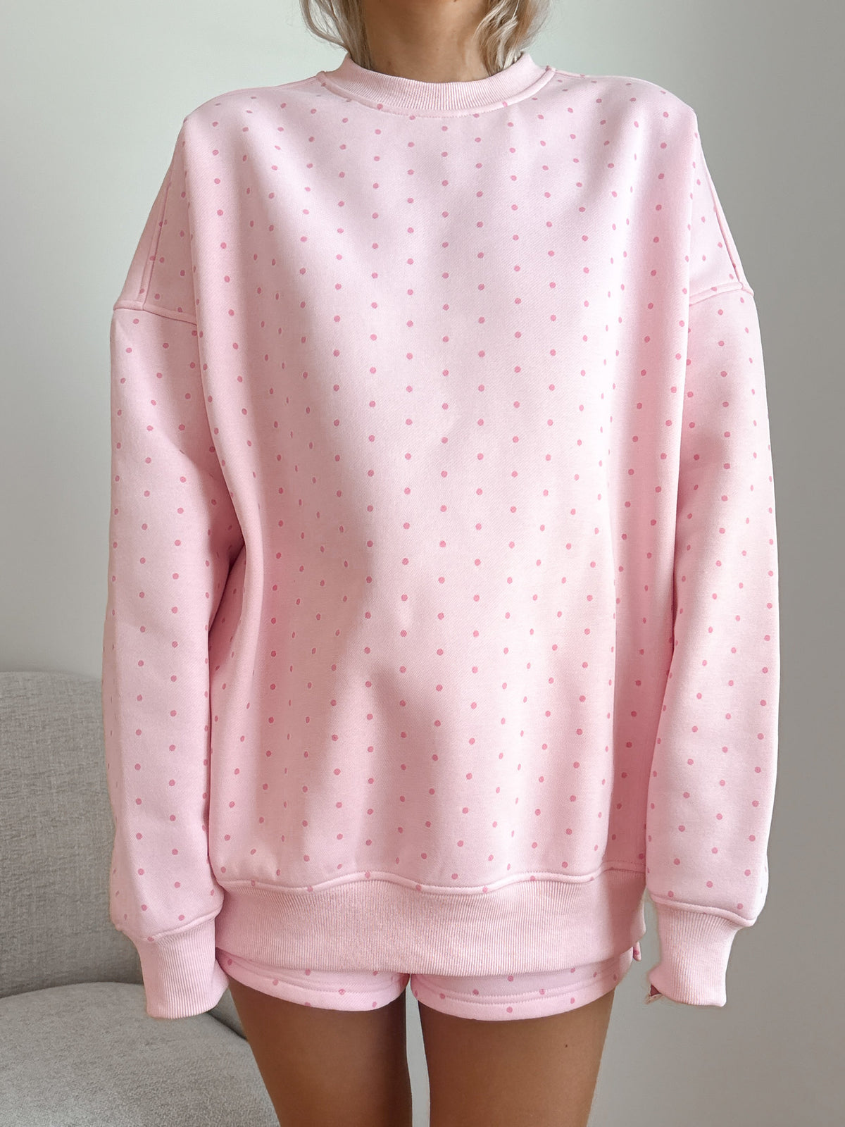 Pink polka dot sweatshirt and shorts set on a neutral background