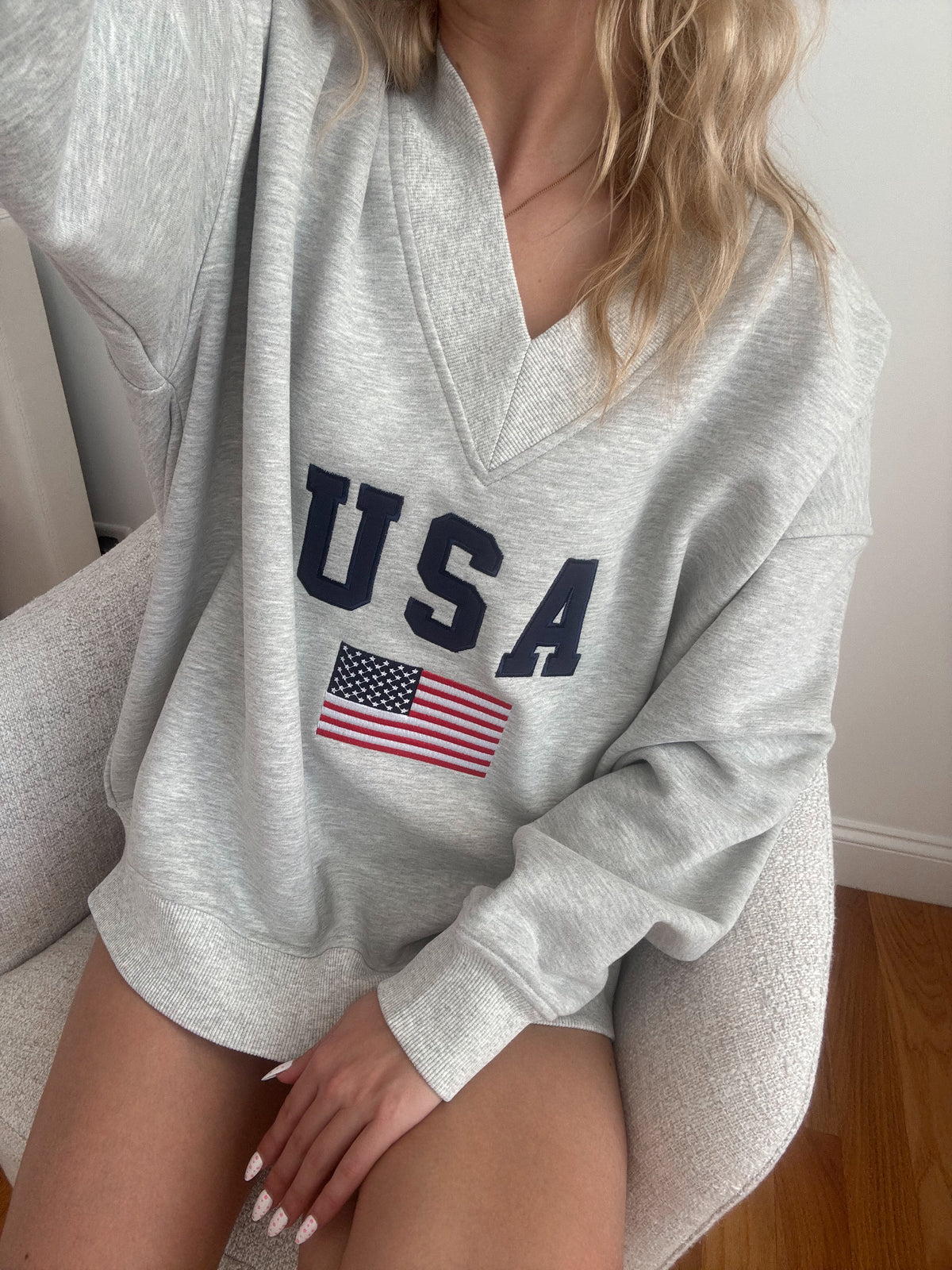 Gray sweatshirt with 'USA' and American flag design worn by a person.