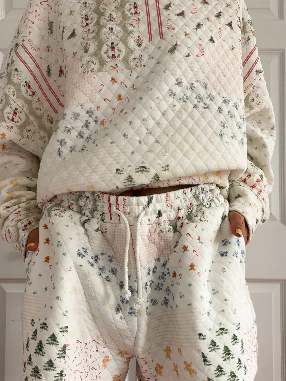 Floral-patterned quilt draped over a person wearing matching pajamas against a neutral background.
