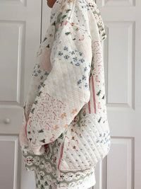 Floral-patterned quilt draped over a person against a white background